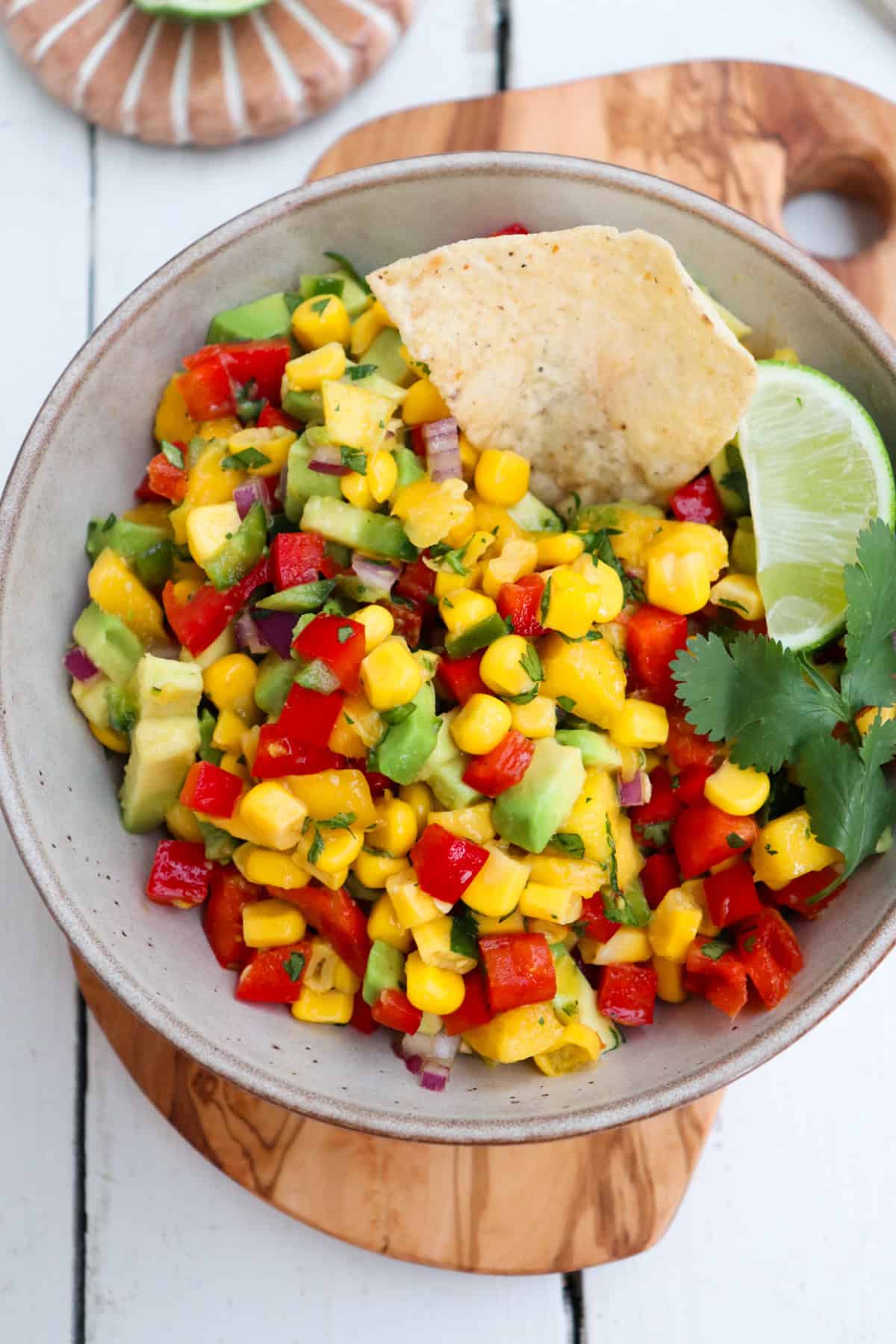 bowl of mango corn salsa with a chip scooping.