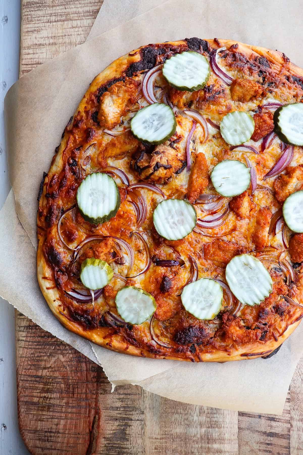 finished nashville hot chicken pizza with dill pickles on top.