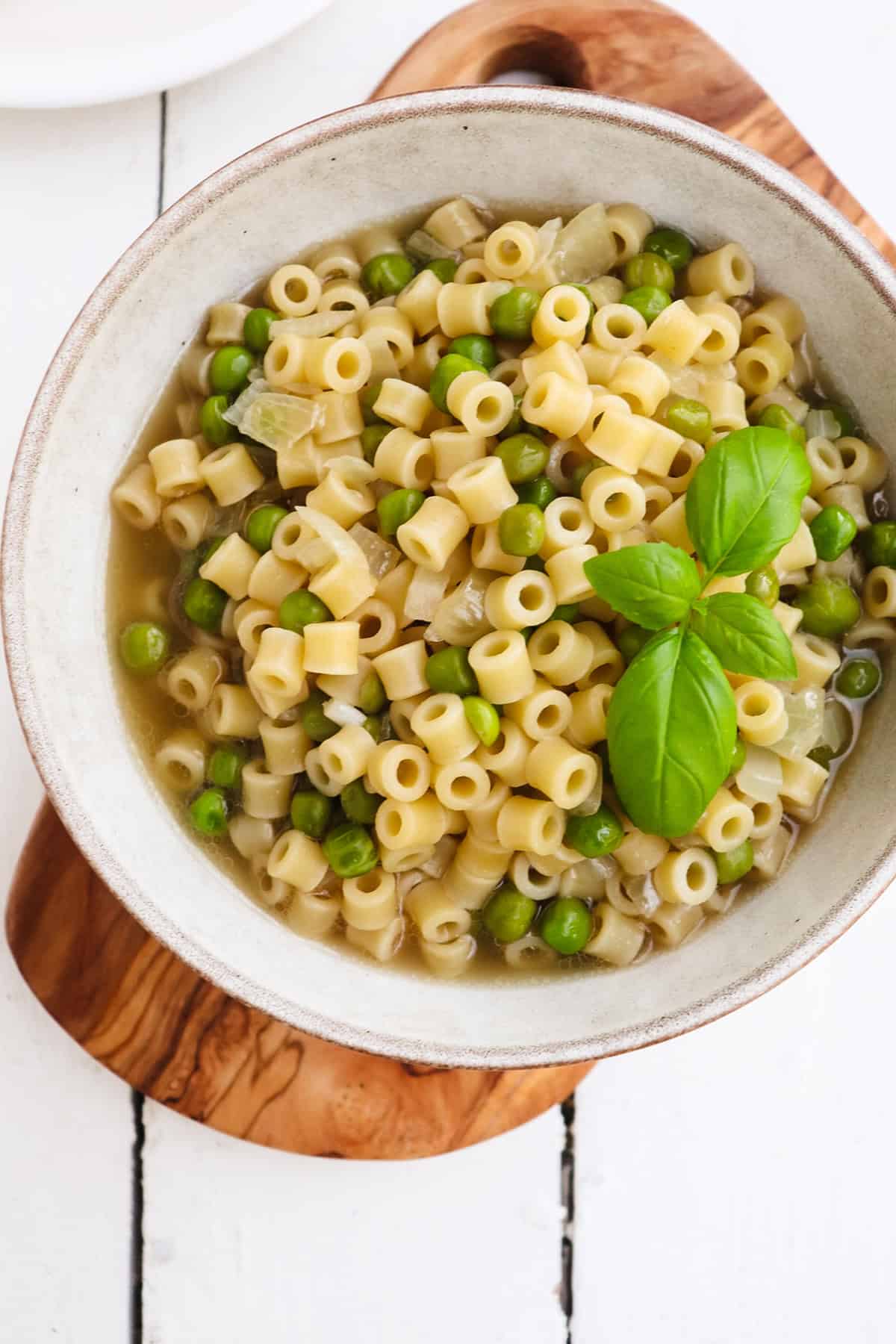 bowl of piselli and pasta garnished with basil.