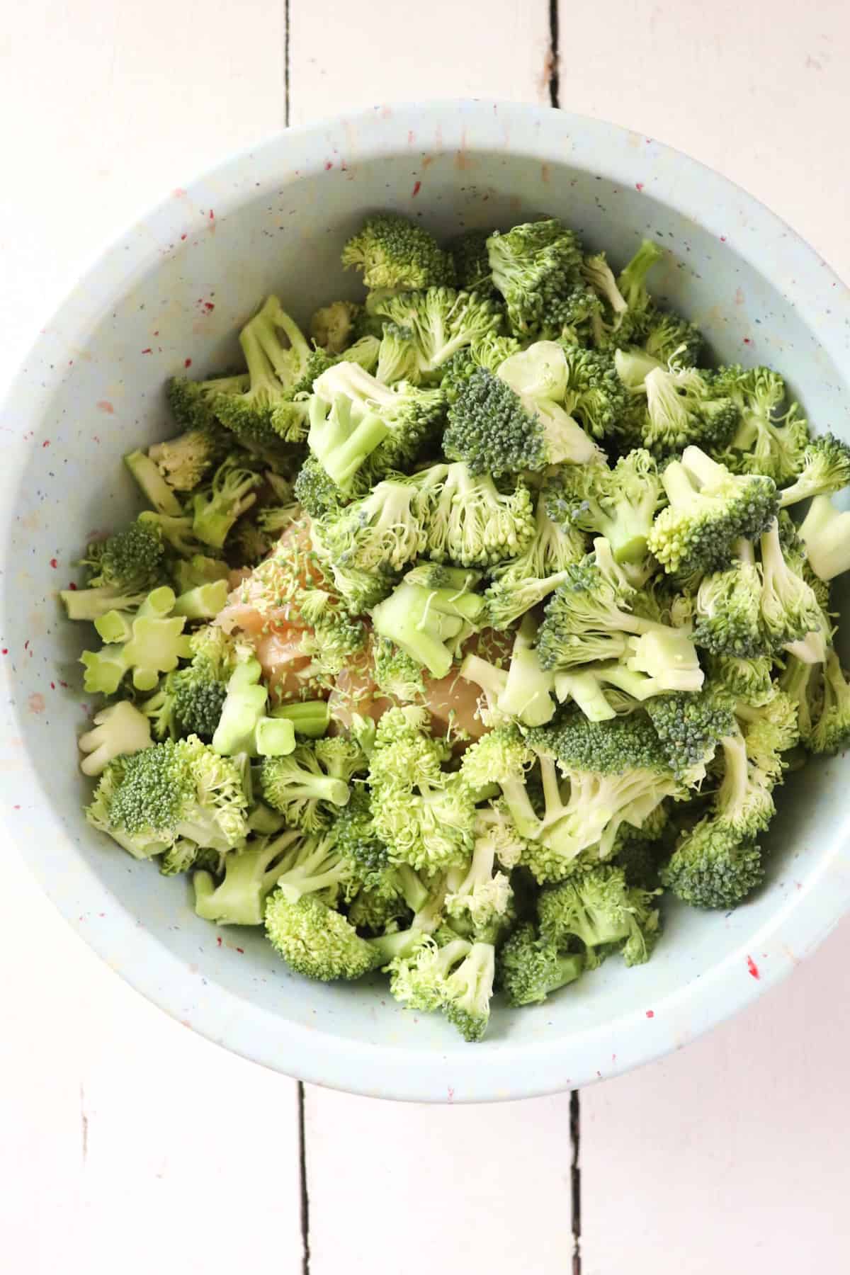 broccoli florets added to blue mixing bowl.