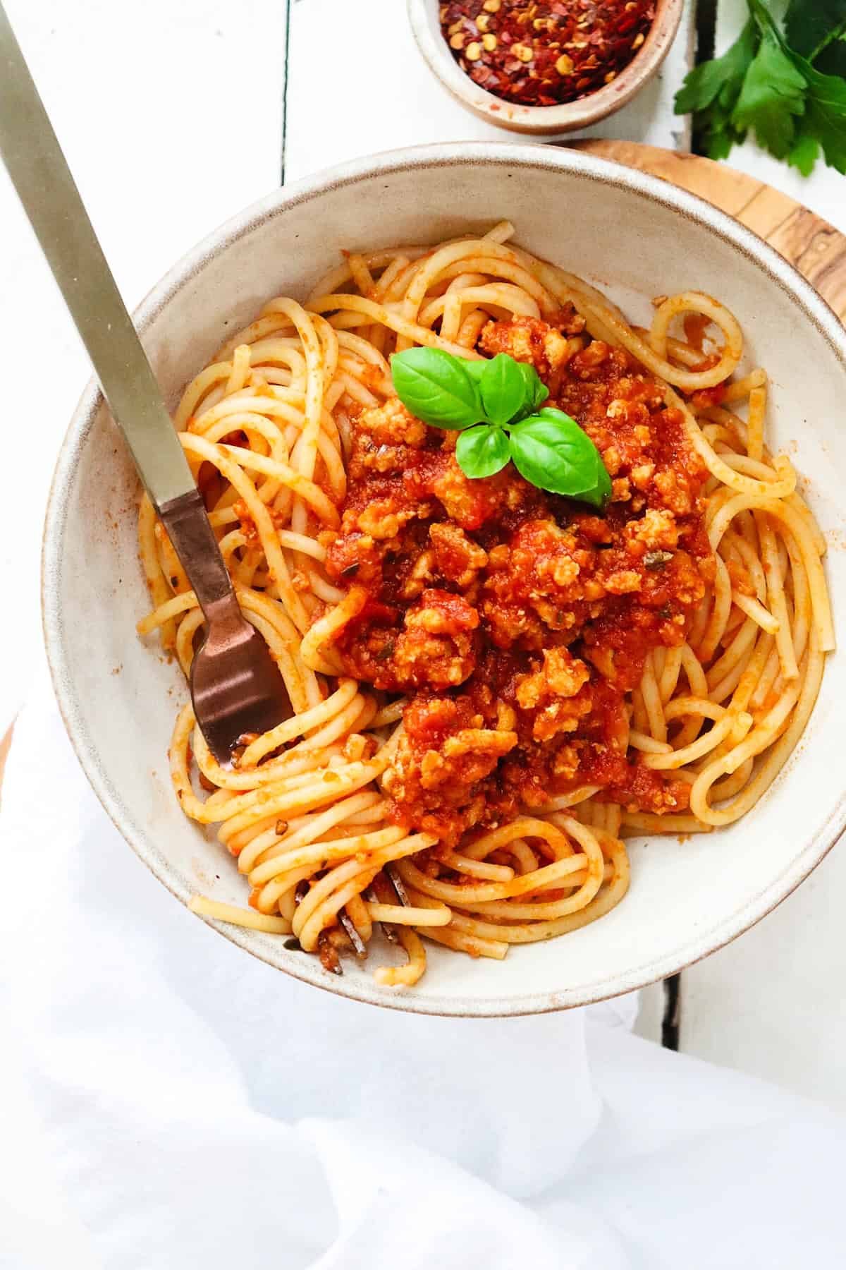 chicken spaghetti in a bowl with basil garnish.