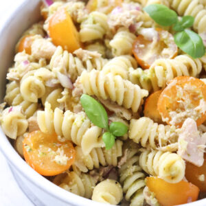 bowl of tuna pesto pasta garnished with fresh basil.