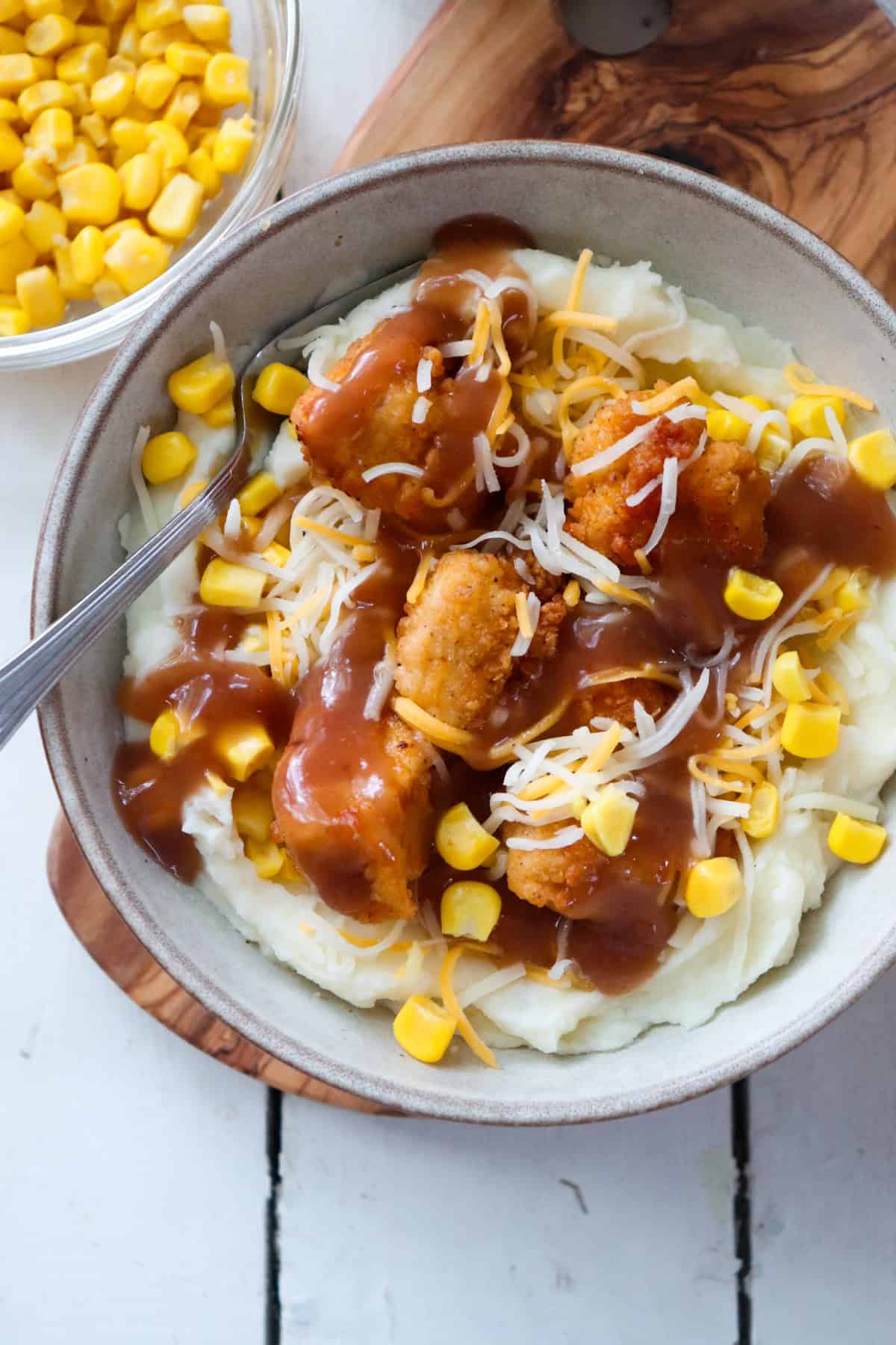 finished copycat kfc famous bowl in a grey bowl with corn on the side.