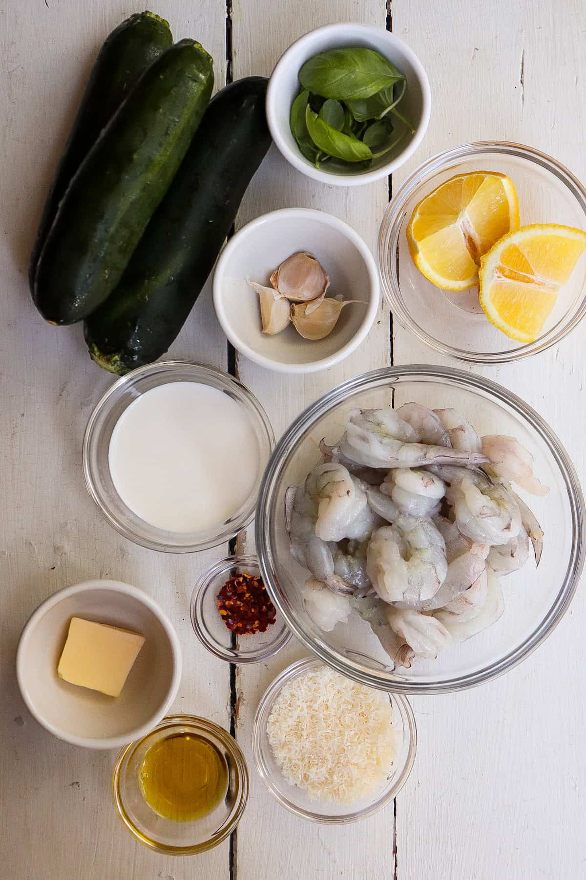 ingredients for shrimp and zucchini noodles dish on a white table.