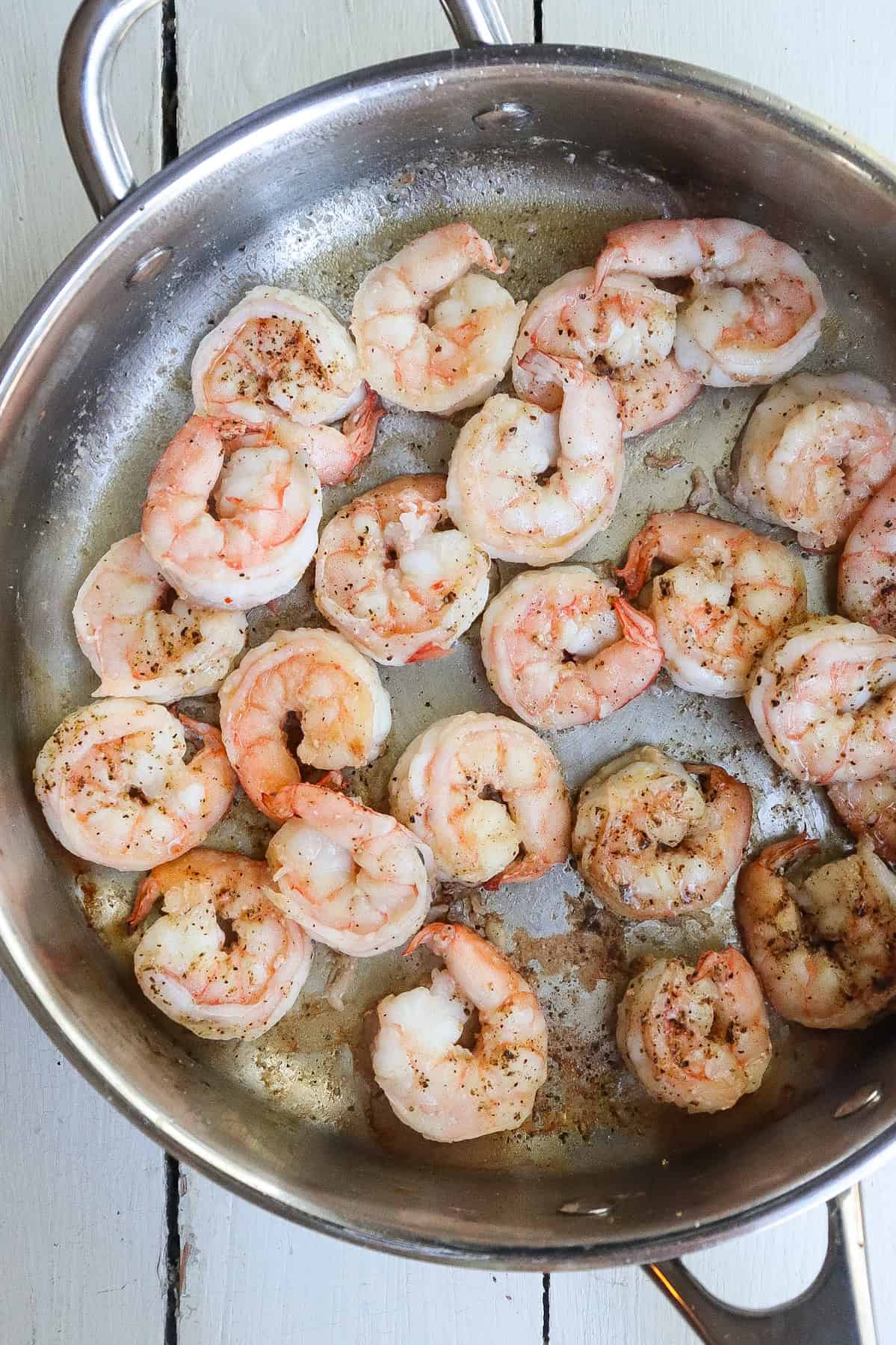 shrimp cooking in a stainless steel skillet.