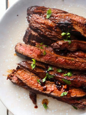 finished marinade steak sliced and on a white plate.