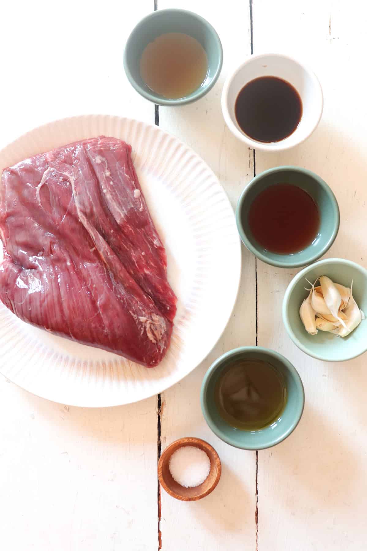 ingredients for cast iron flank steak on a white table. 