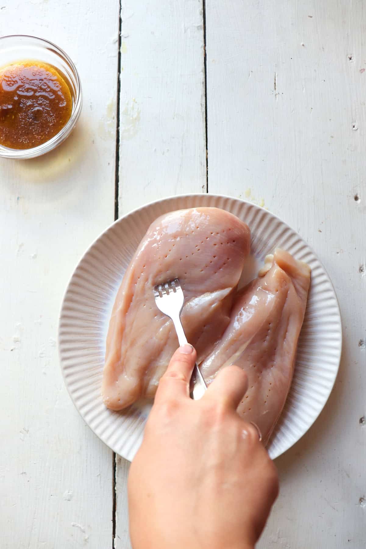 two jacquard chicken breasts on a plate being poked with a fork.