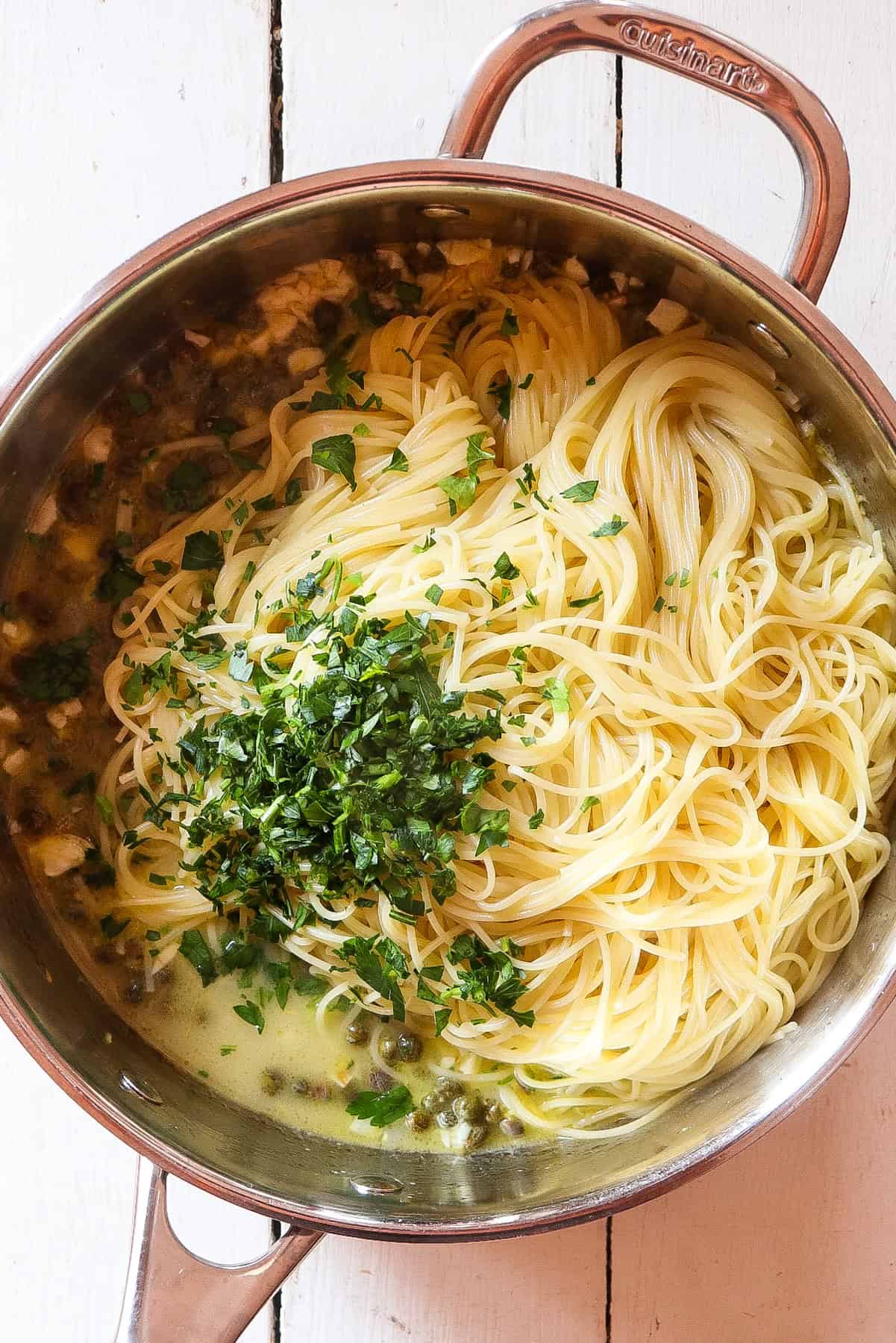 fresh parsley added to pasta in skillet.