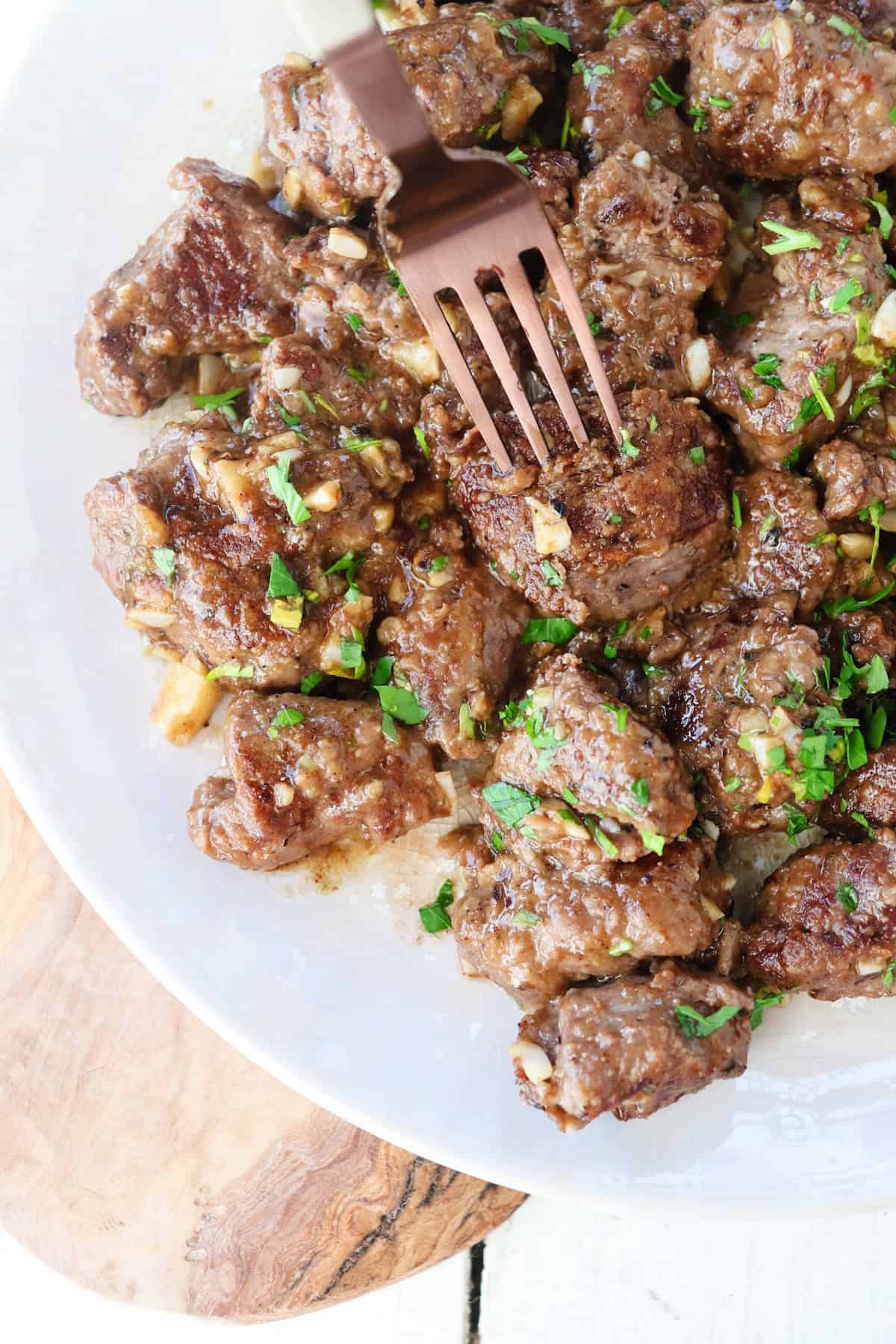 Beef tenderloin tips with garlic on serving plate.