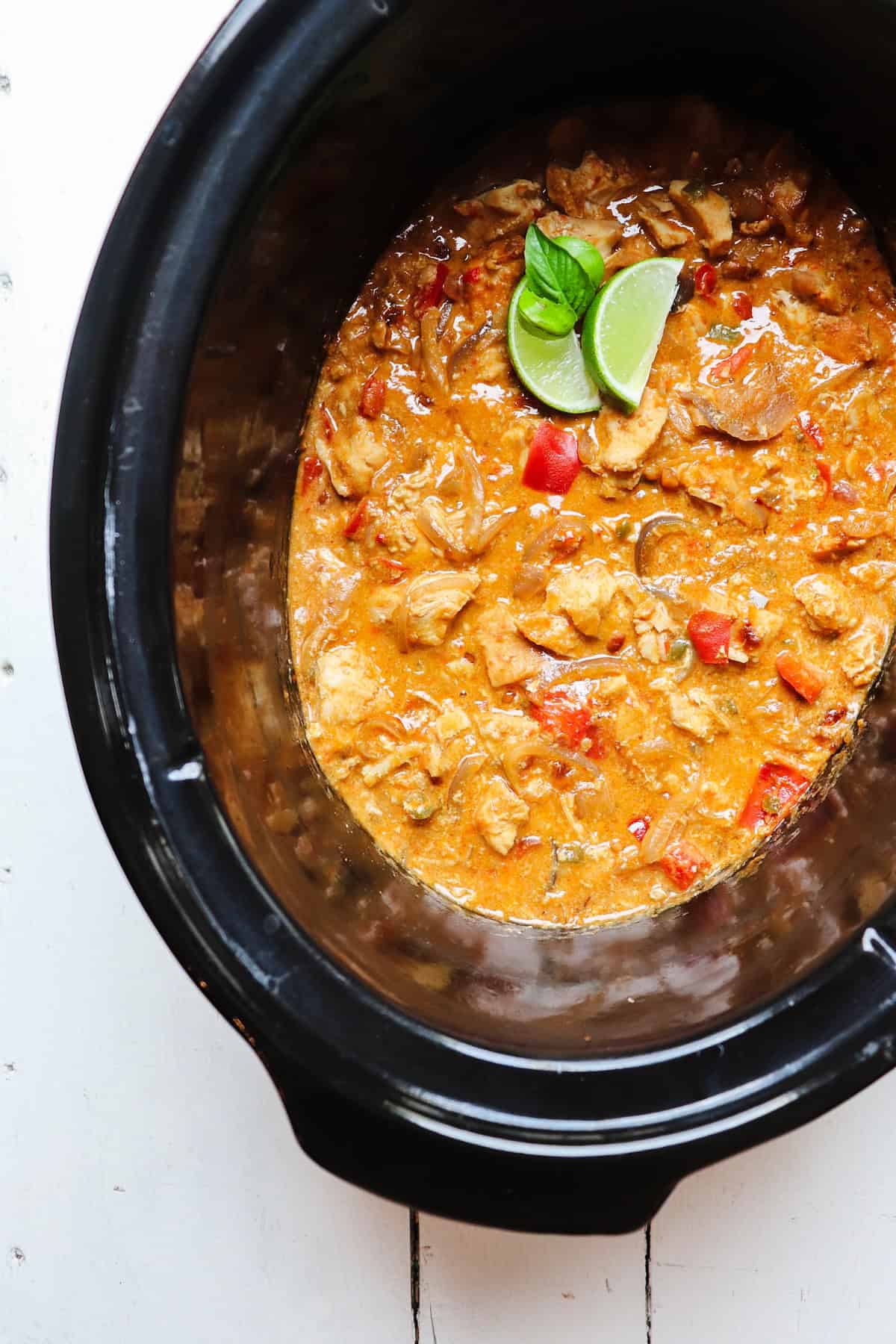 finished dish in crockpot with limes and basil for garnish.