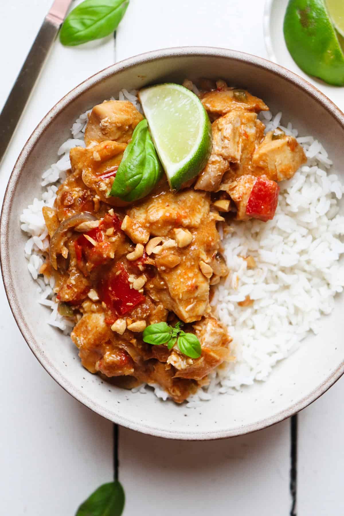 plated crock pot chicken satay with peanut sauce topped with lime and basil.