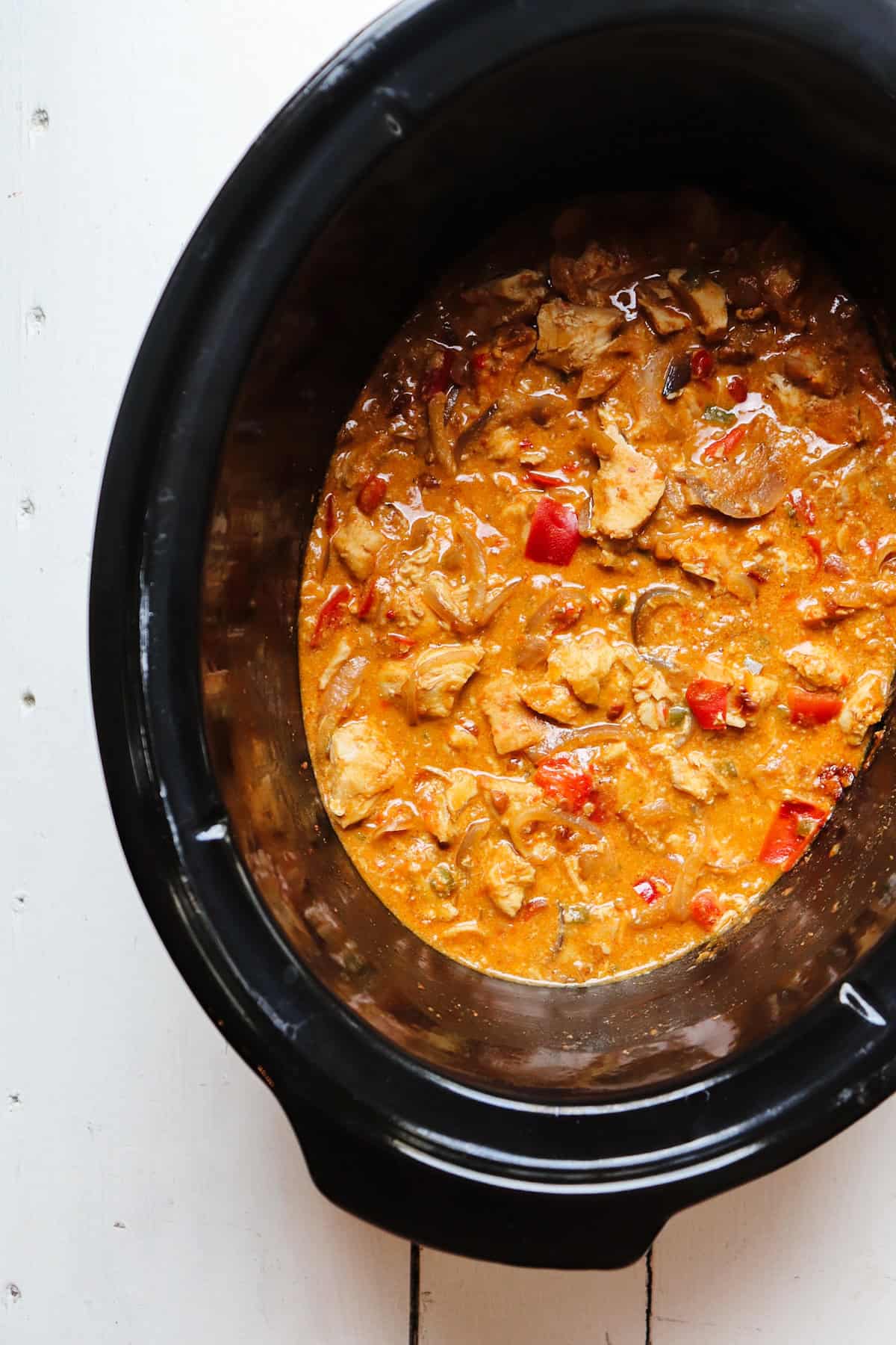 finished chicken satay in black slow cooker.