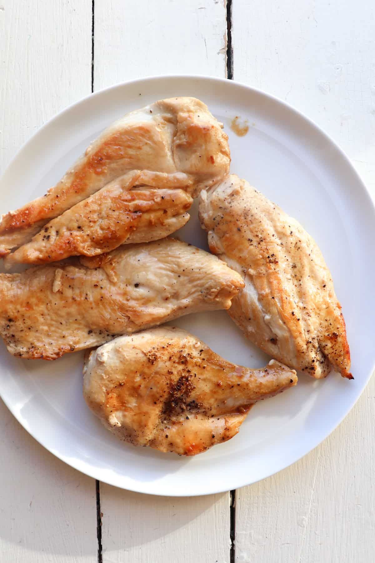 cooked thin cut chicken breasts on plate.