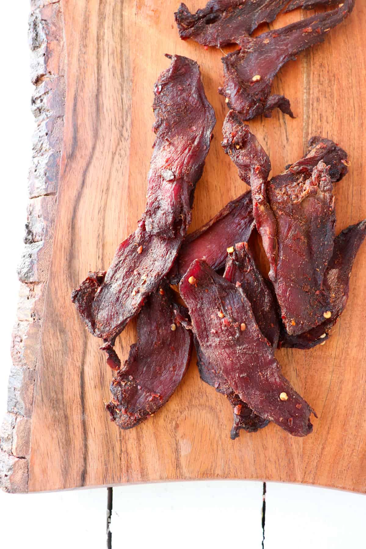 Venison jerky on wooden cutting board.