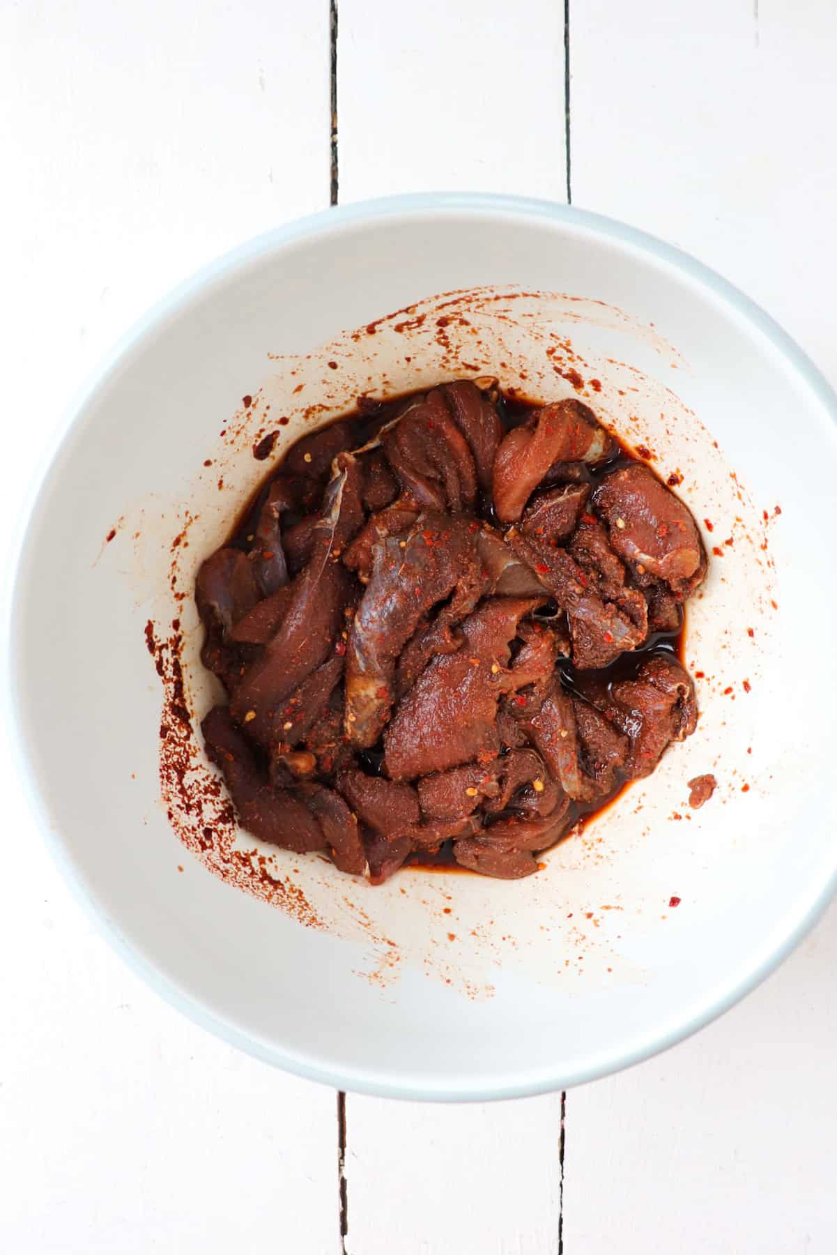 Venison in marinade in bowl.