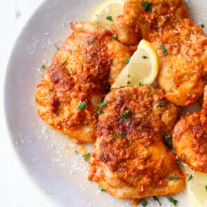 parmesan garlic chicken thighs on a plate up close.