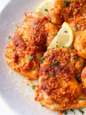 parmesan garlic chicken thighs on a plate up close.