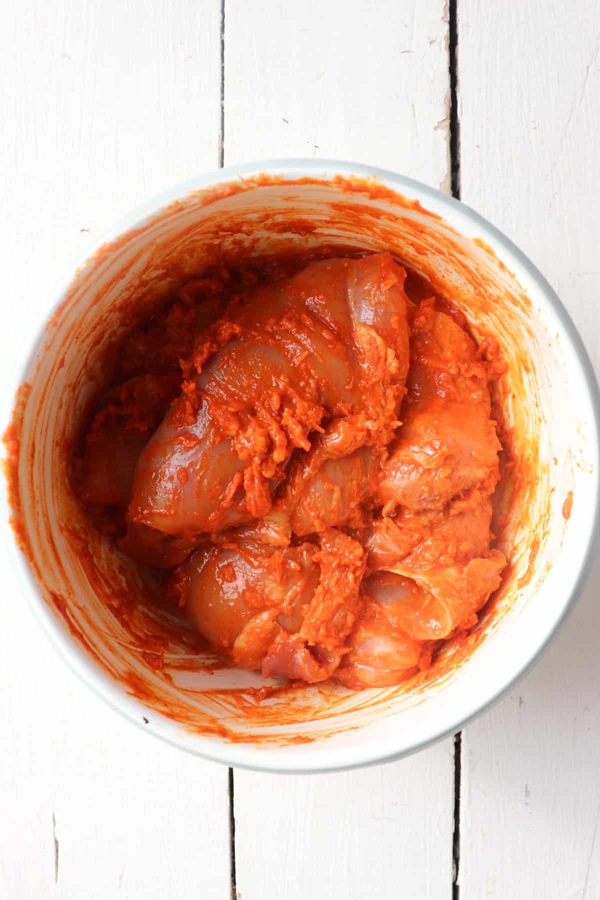 chicken thighs coated in seasoning in a bowl.