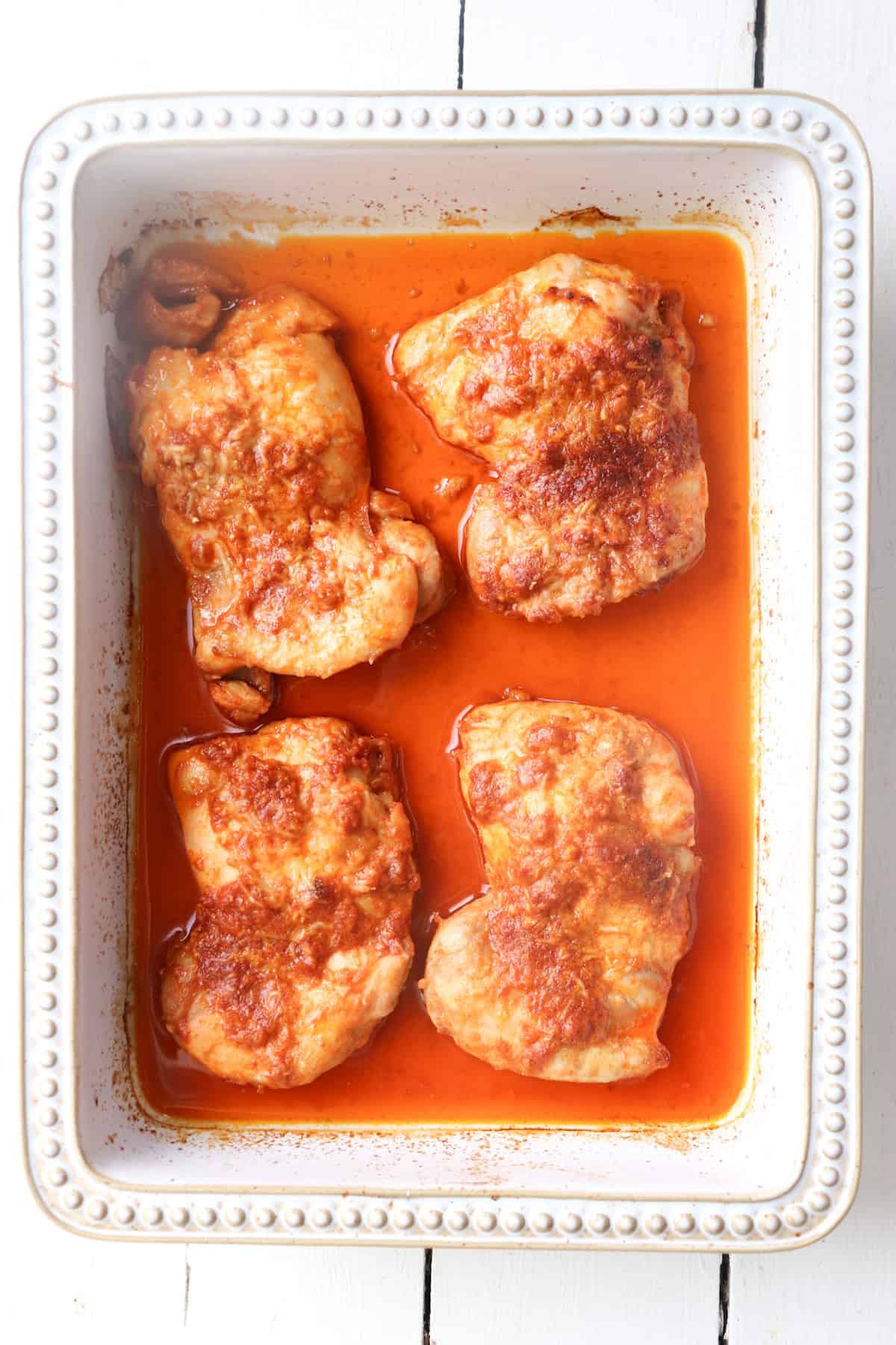 baked chicken thighs in a white dish.