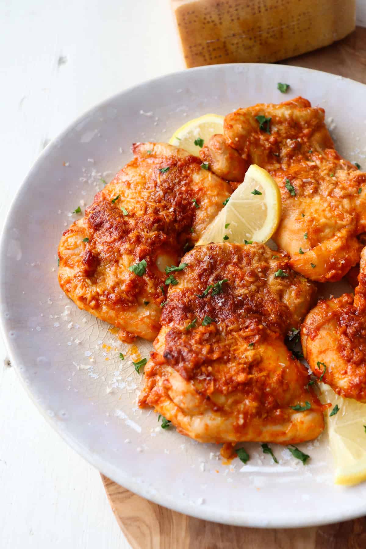 chicken thighs on a white plate garnished with lemon.