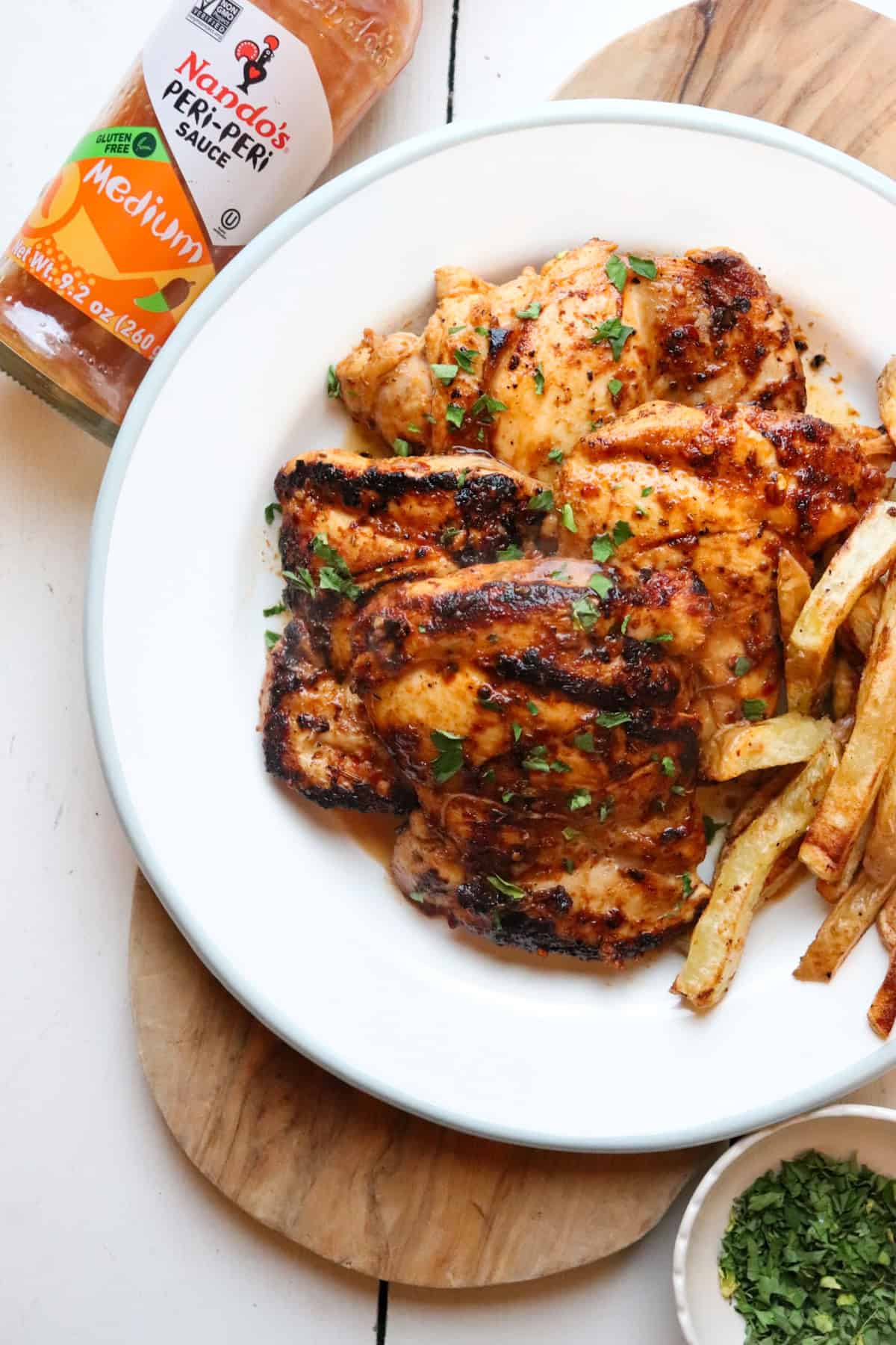 plate of chicken and fries with nandos sauce in the background.