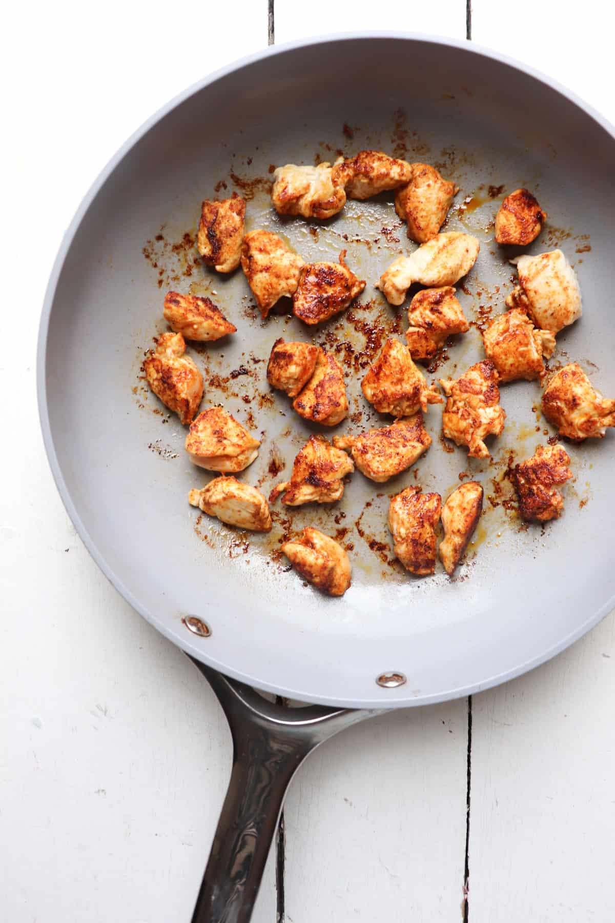 Diced chicken cooked in pan.