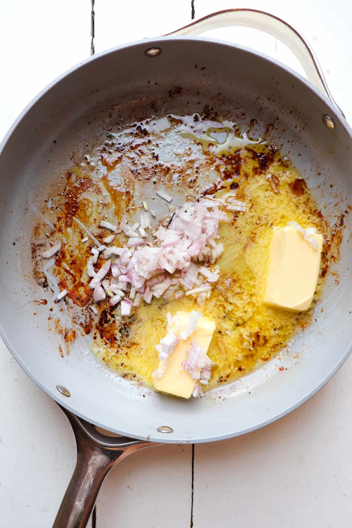 A pan with butter and shallots in it.