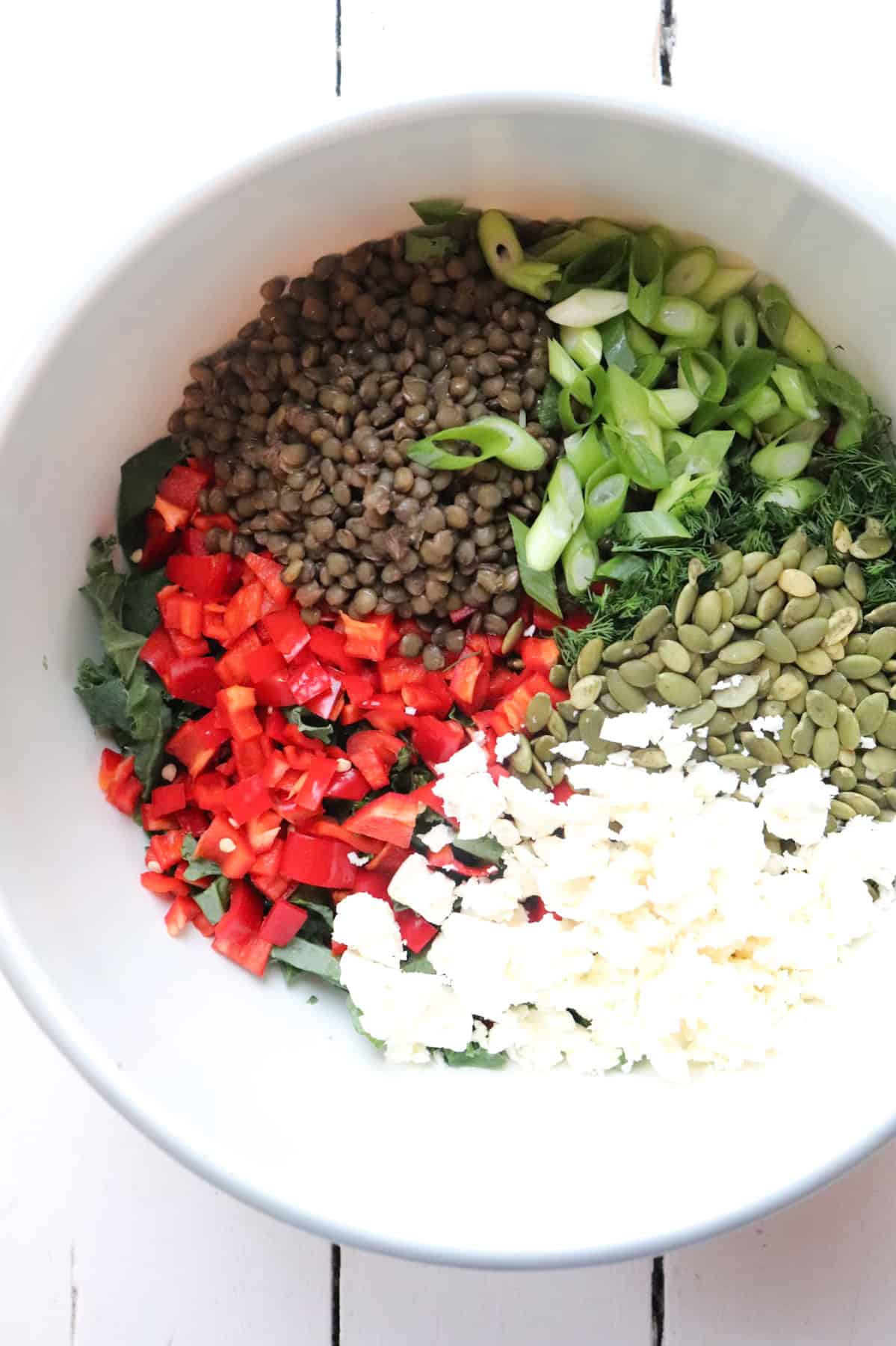 salad ingredients added to a large bowl but unmixed.