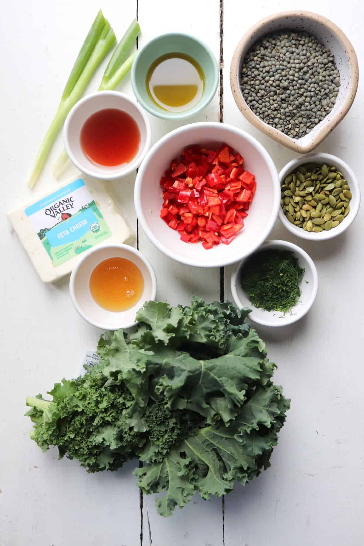 ingredients for kale and lentil salad on a white table.