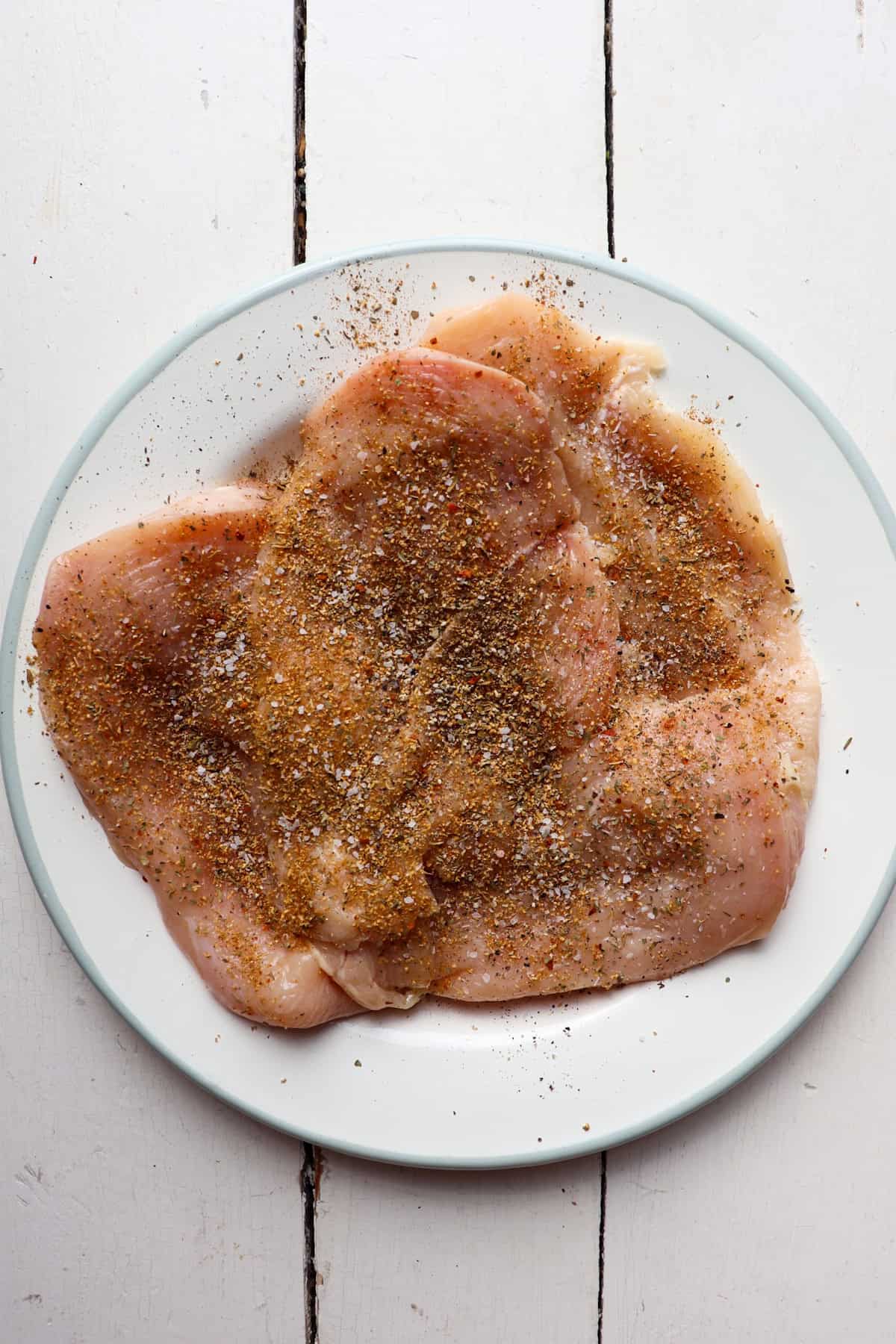 4 pieces of chicken on a plate with spices.