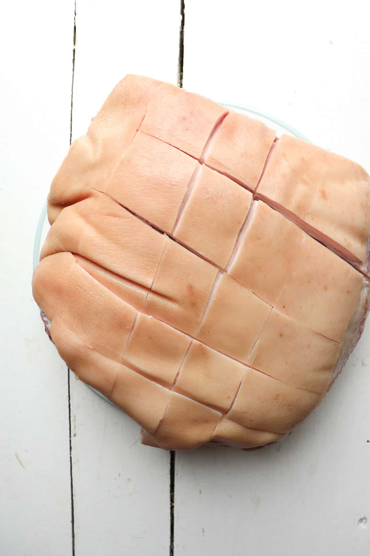 skin cap of pork shoulder sliced with a criss cross pattern.