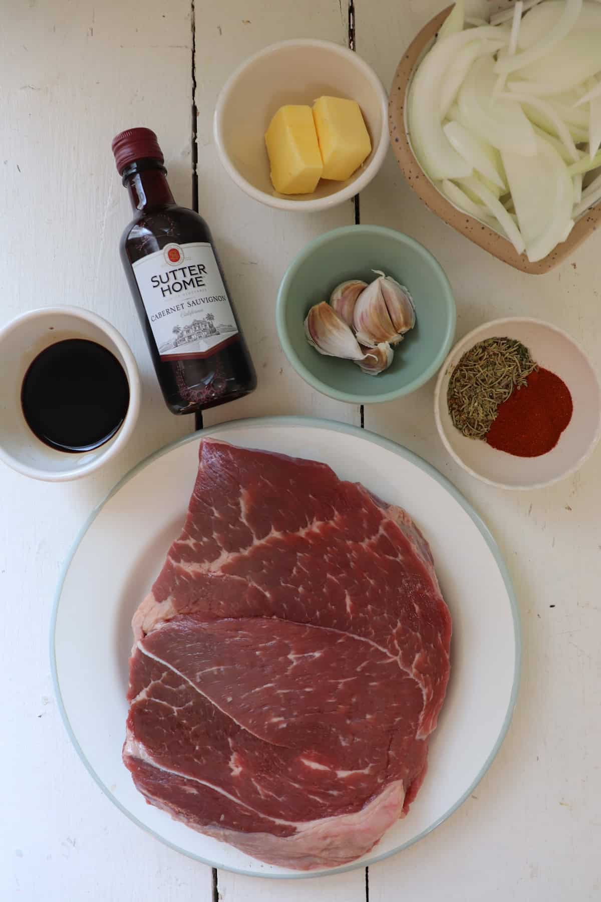 Ingredients for a beef stew on a white table.