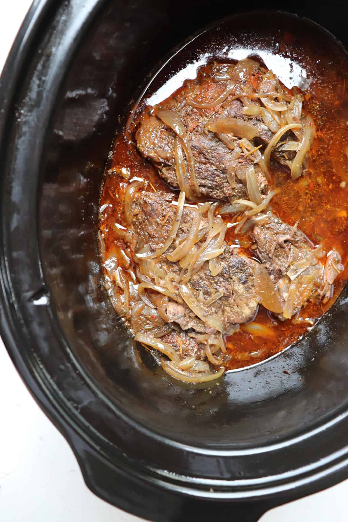 finished roast in black slow cooker before it has been shredded.