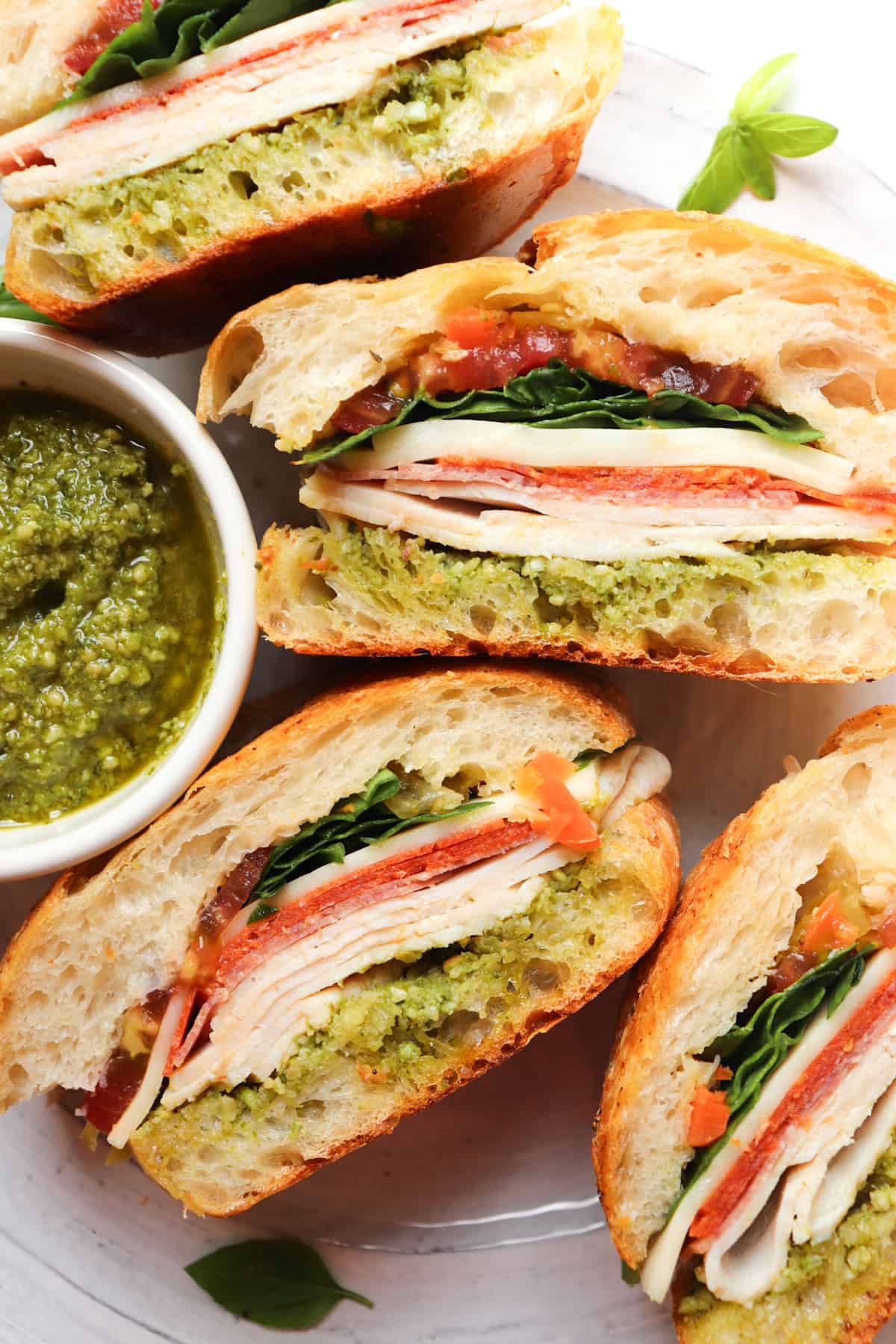 turkey pesto sandwich cut in pieces and laid on side to show layers.