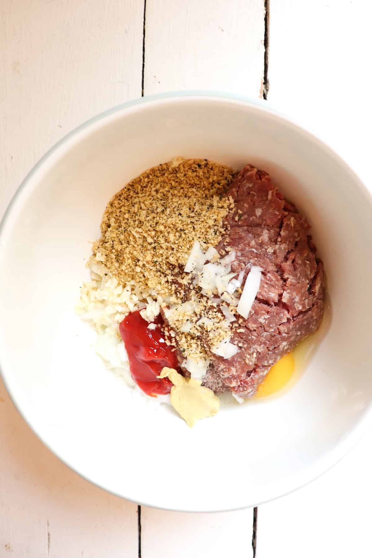 ingredients for venison salisbury steaks in a white mixing bowl.