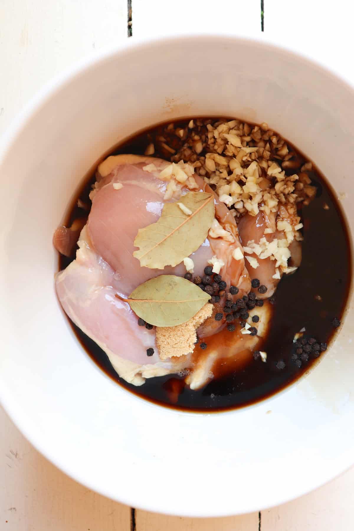 chicken and marinade unmixed in a white bowl.