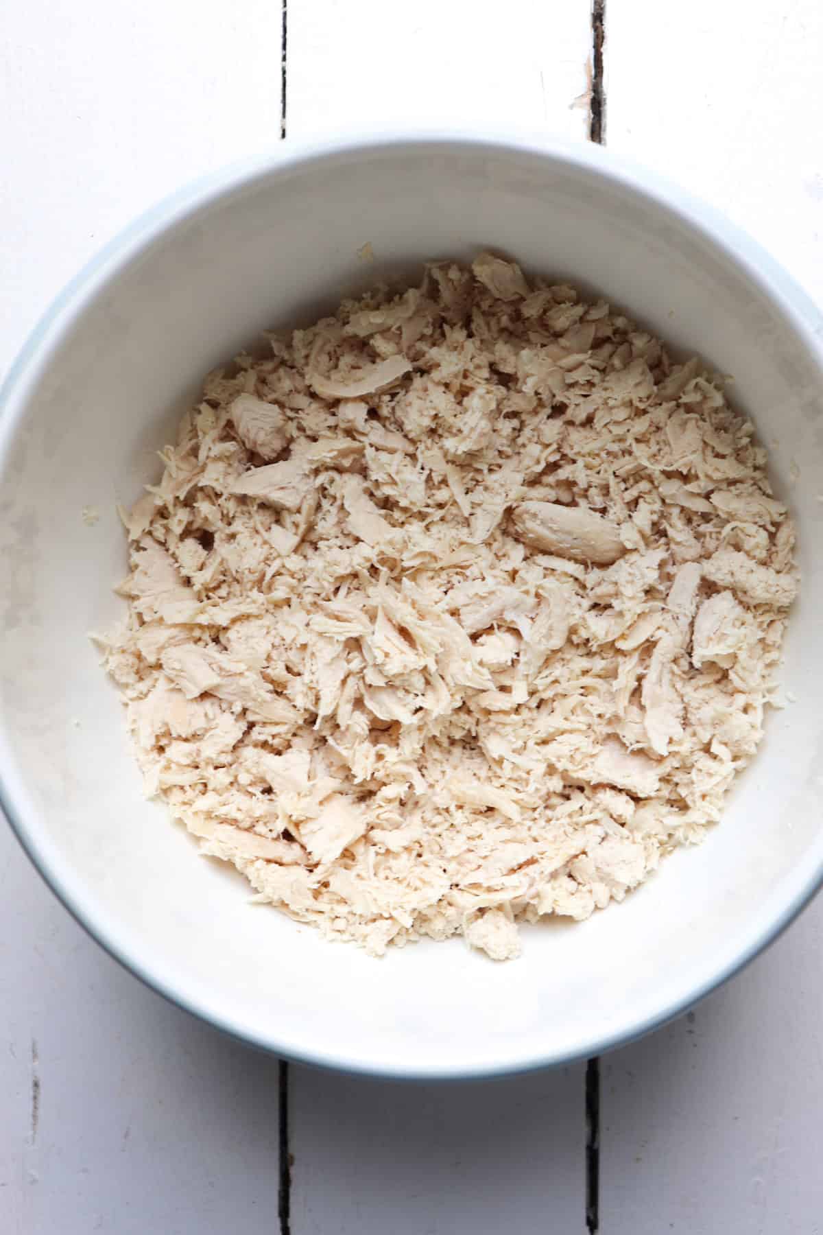 shredded chicken tenderloins in a white bowl.