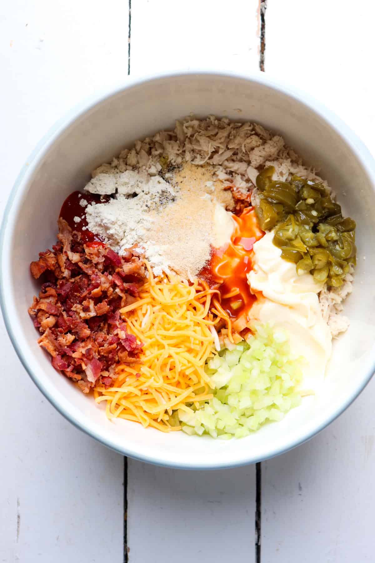 seasonings added to shredded chicken in a white bowl.