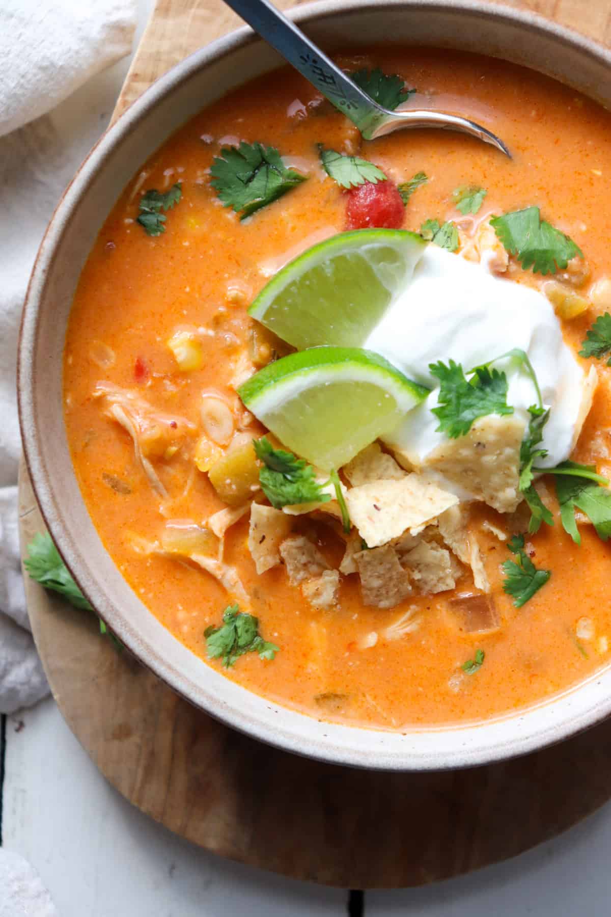 bowl of creamy chicken enchilada soup with garnishes up close.