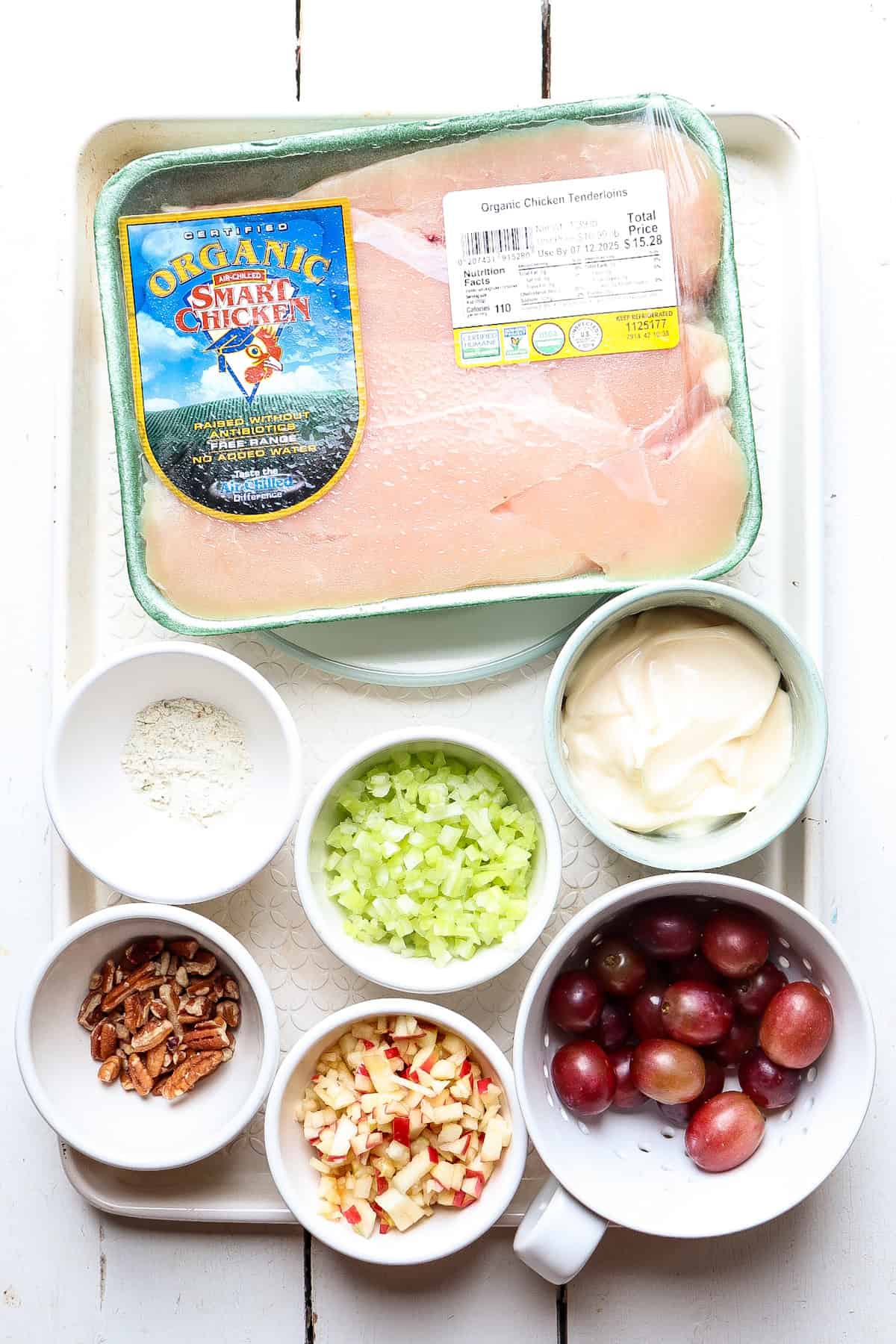 Ingredients for chicken salad in bowls on a table.