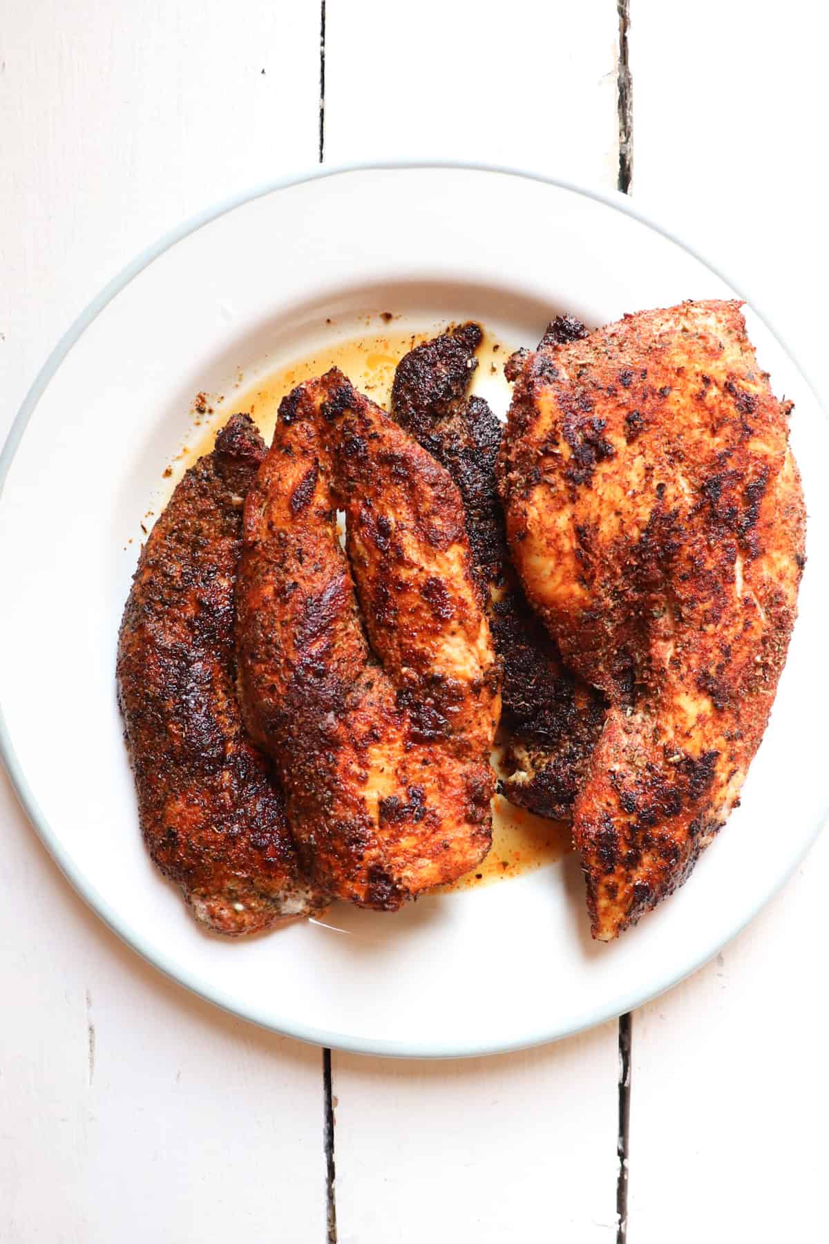 four finished chicken pieces on a white plate.