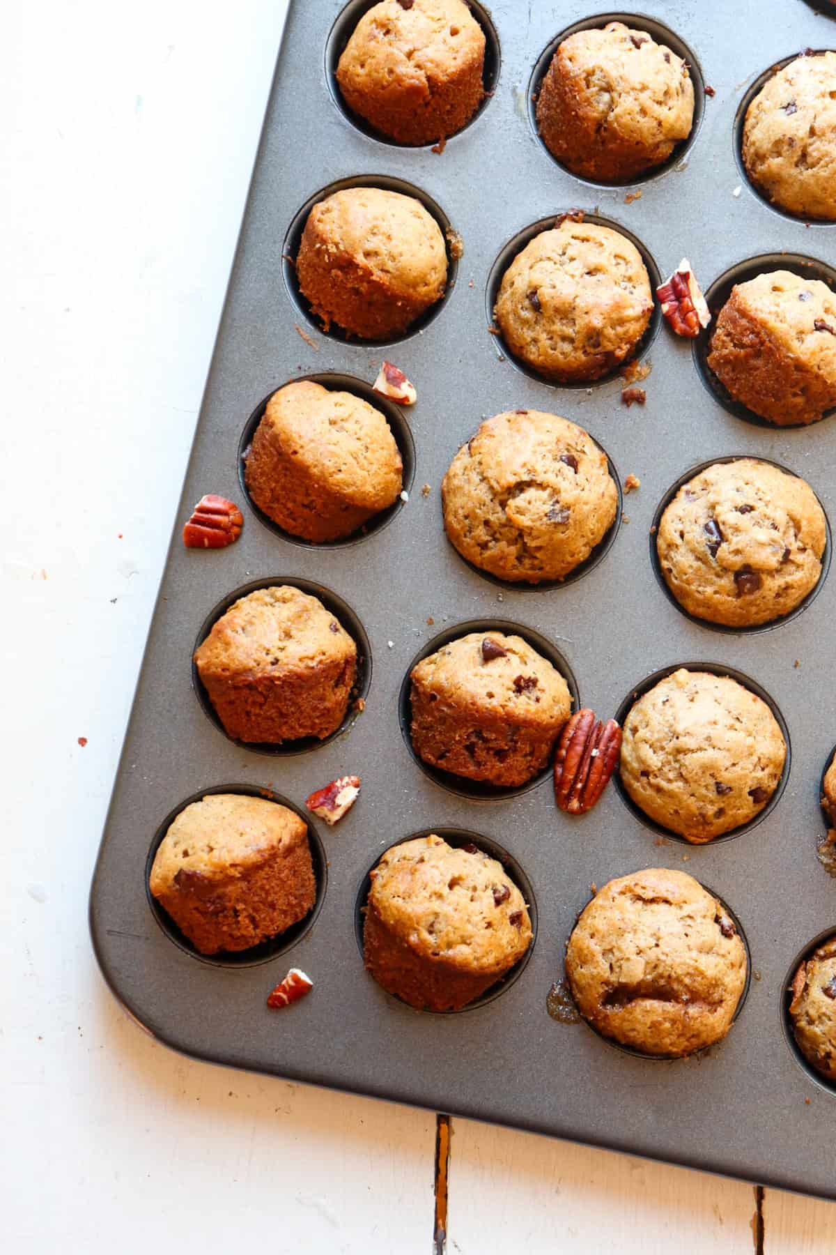 banana nut mini muffin in muffin tin with pecans.