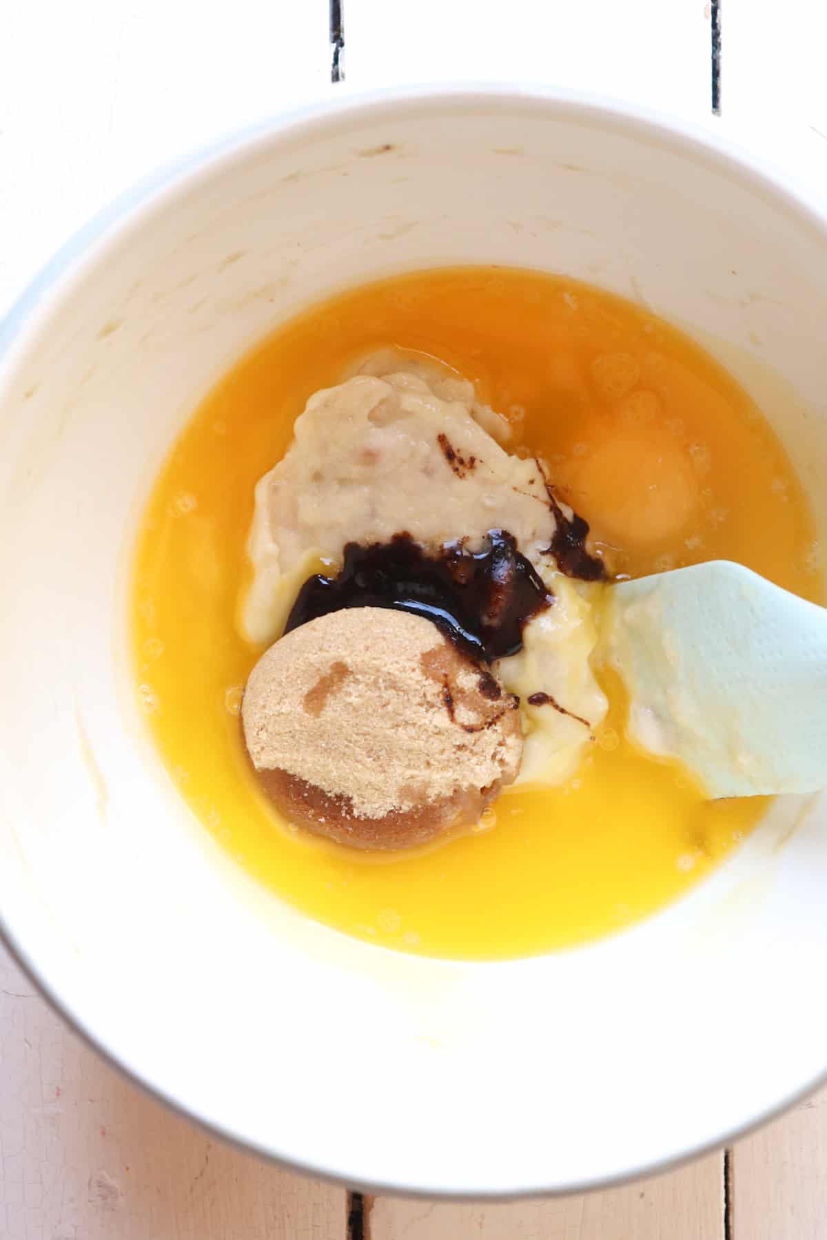 Wet ingredients in mixing bowl for banana nut mini muffins.