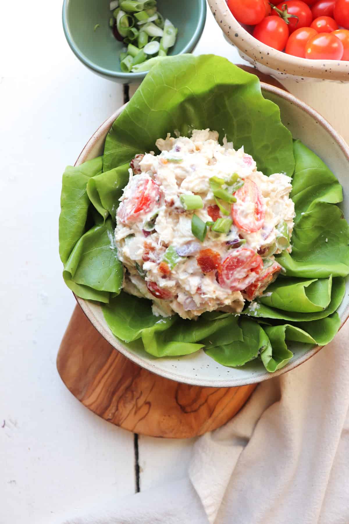 blt chicken salad on a bed of lettuce with tomatoes in the background.