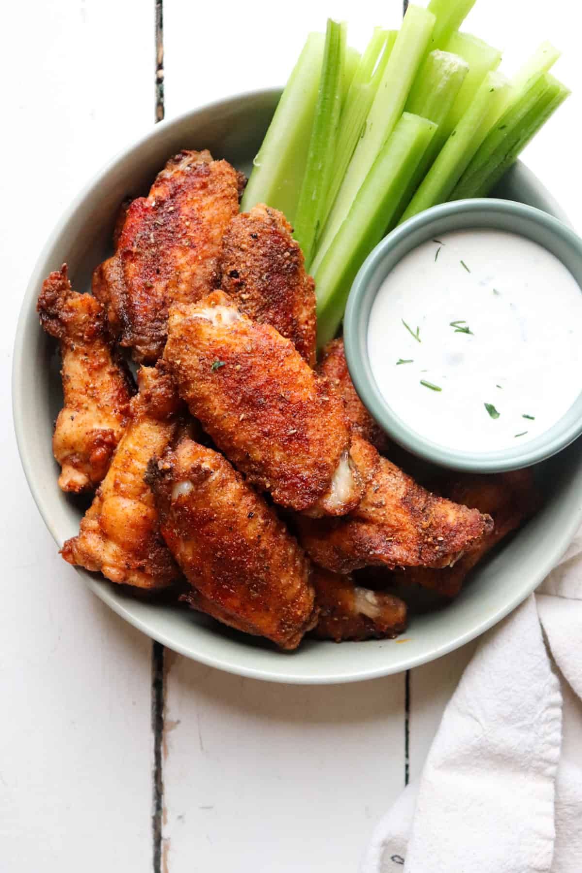 bowl of wings with ranch and celery on a table.