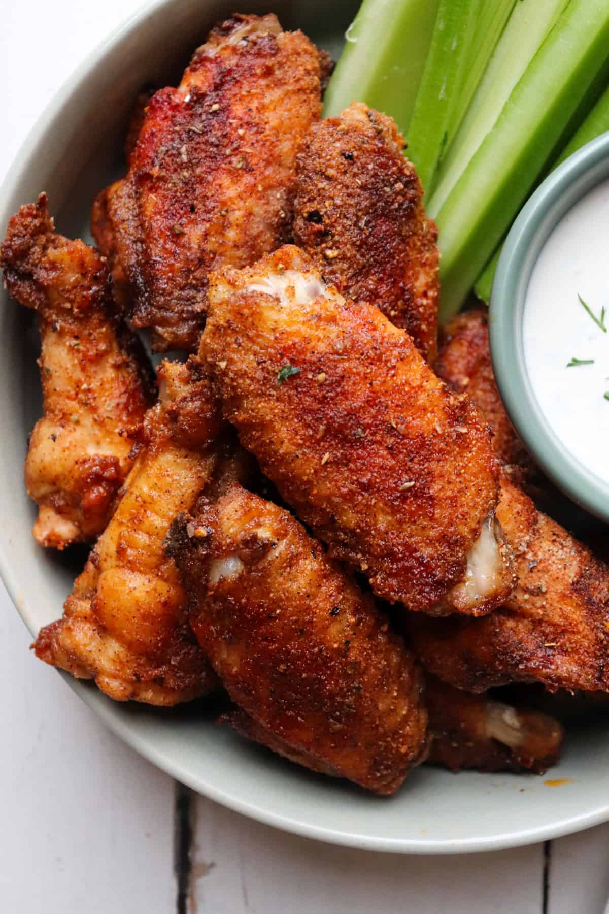 plate of chicken wings with ranch and celery to the side.