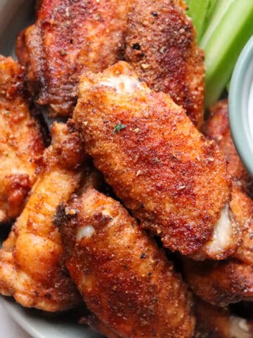 plate of chicken wings with ranch and celery to the side.