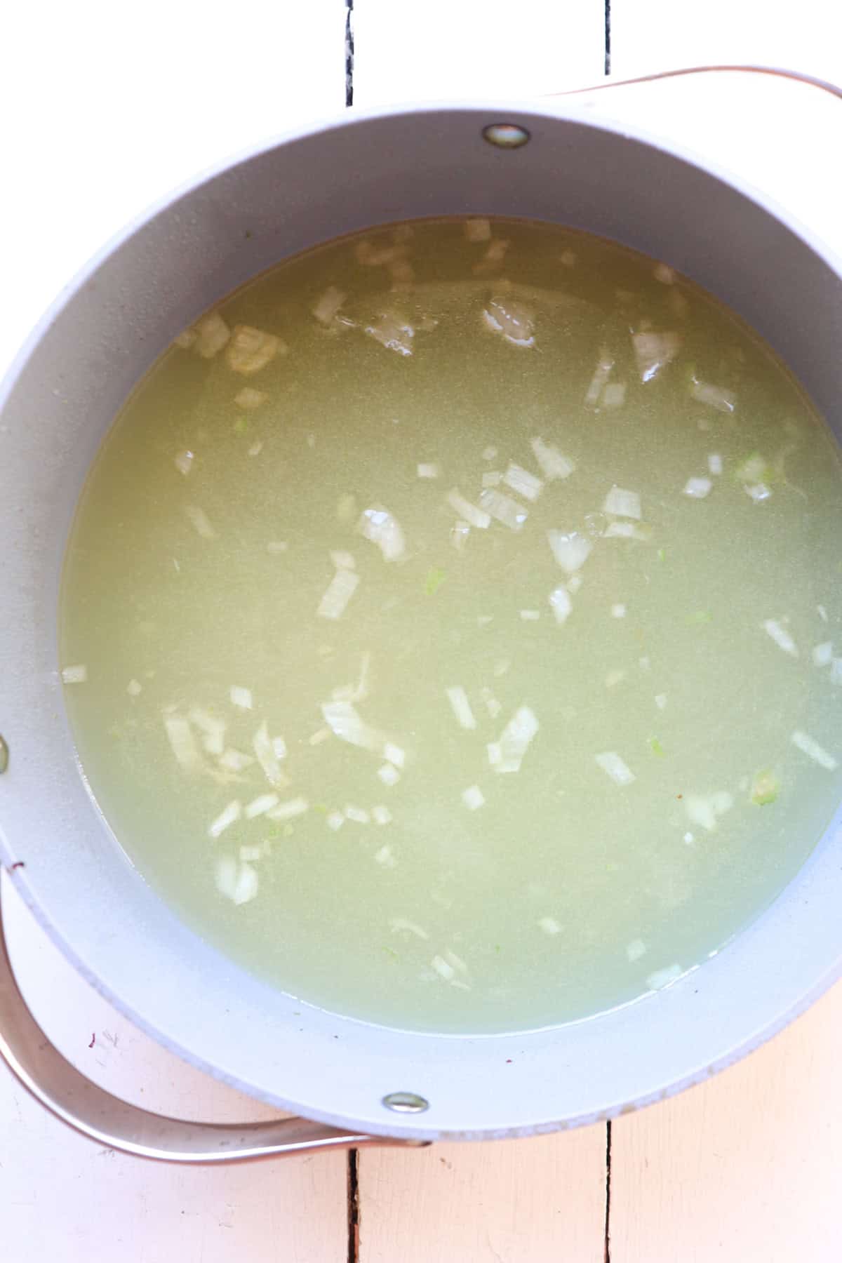 ingredients for greek lemonn rice soup in pot with broth.
