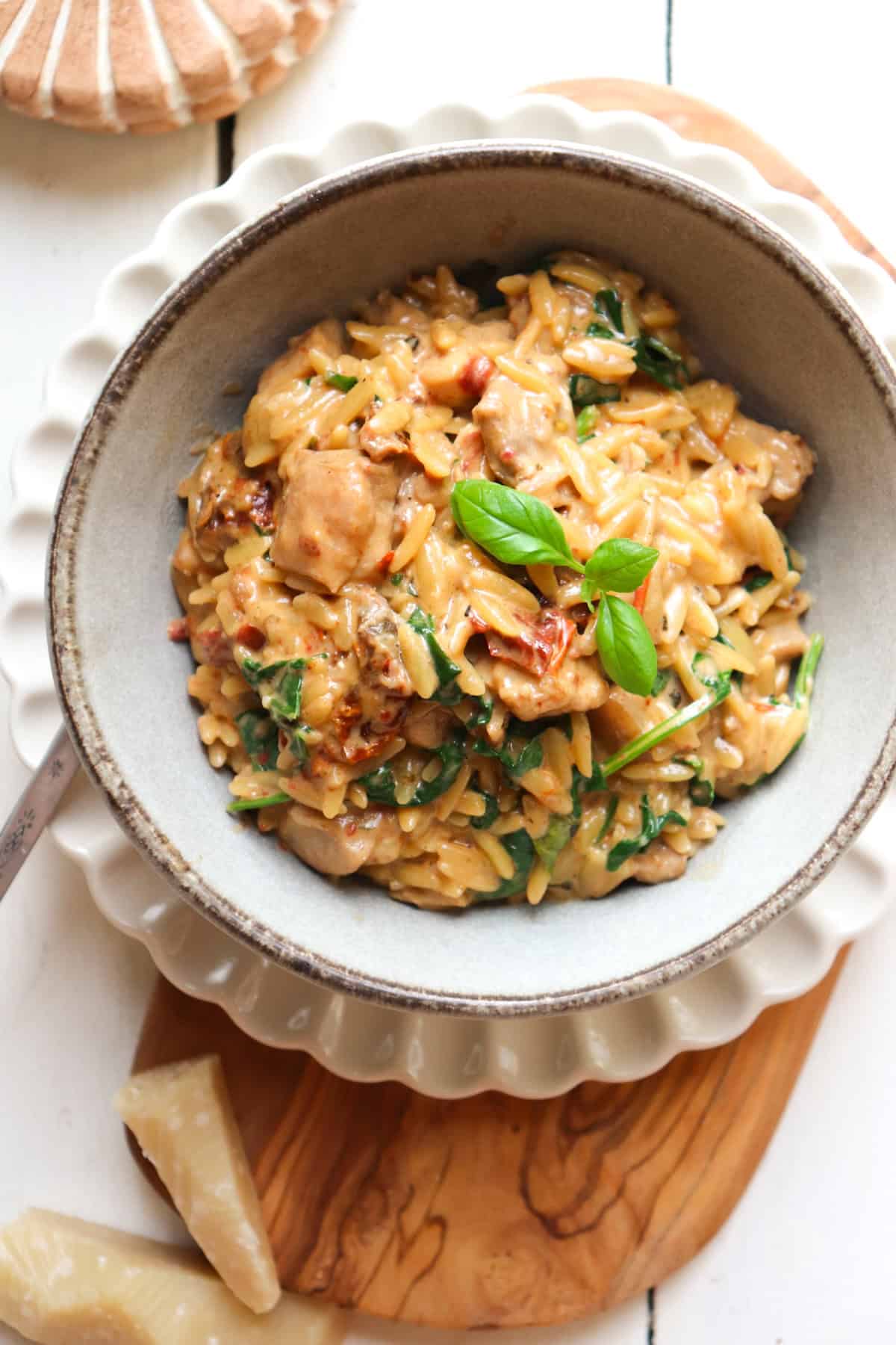 bowl of chicken and orzo in cream sauce with decor around it.